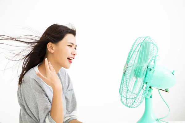 Smiling woman cooling herself by electric fan — Stock Photo, Image