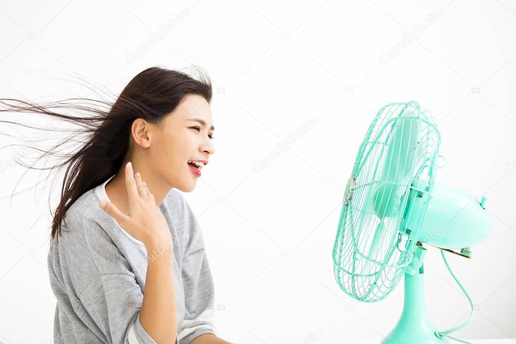 smiling woman cooling herself by electric fan
