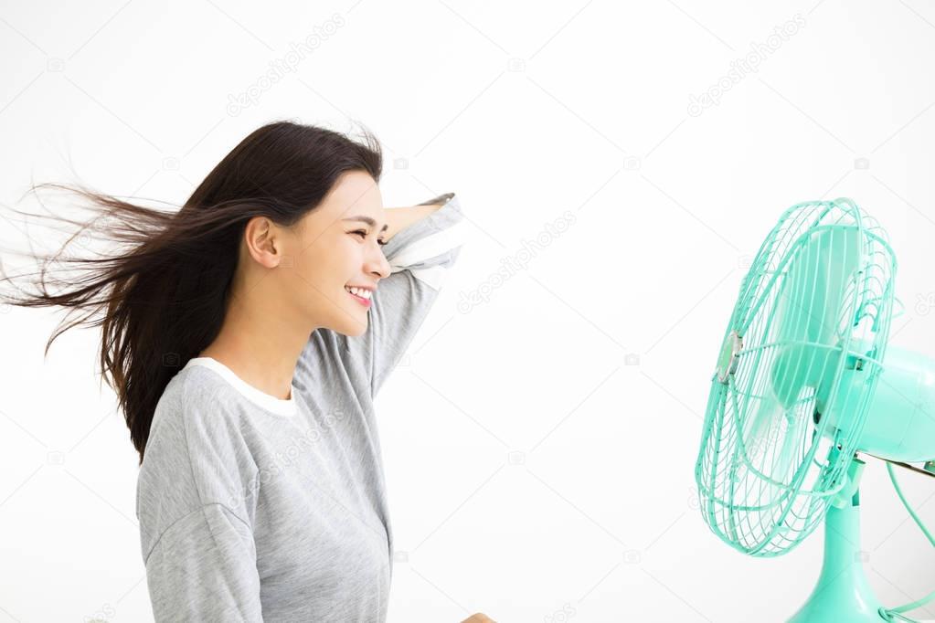 smiling woman cooling herself by electric fan