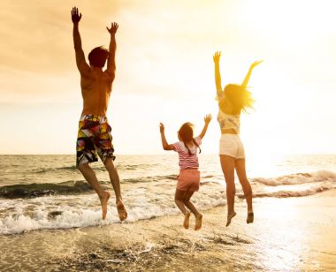 Mutlu bir aile sahilde zıplıyor.