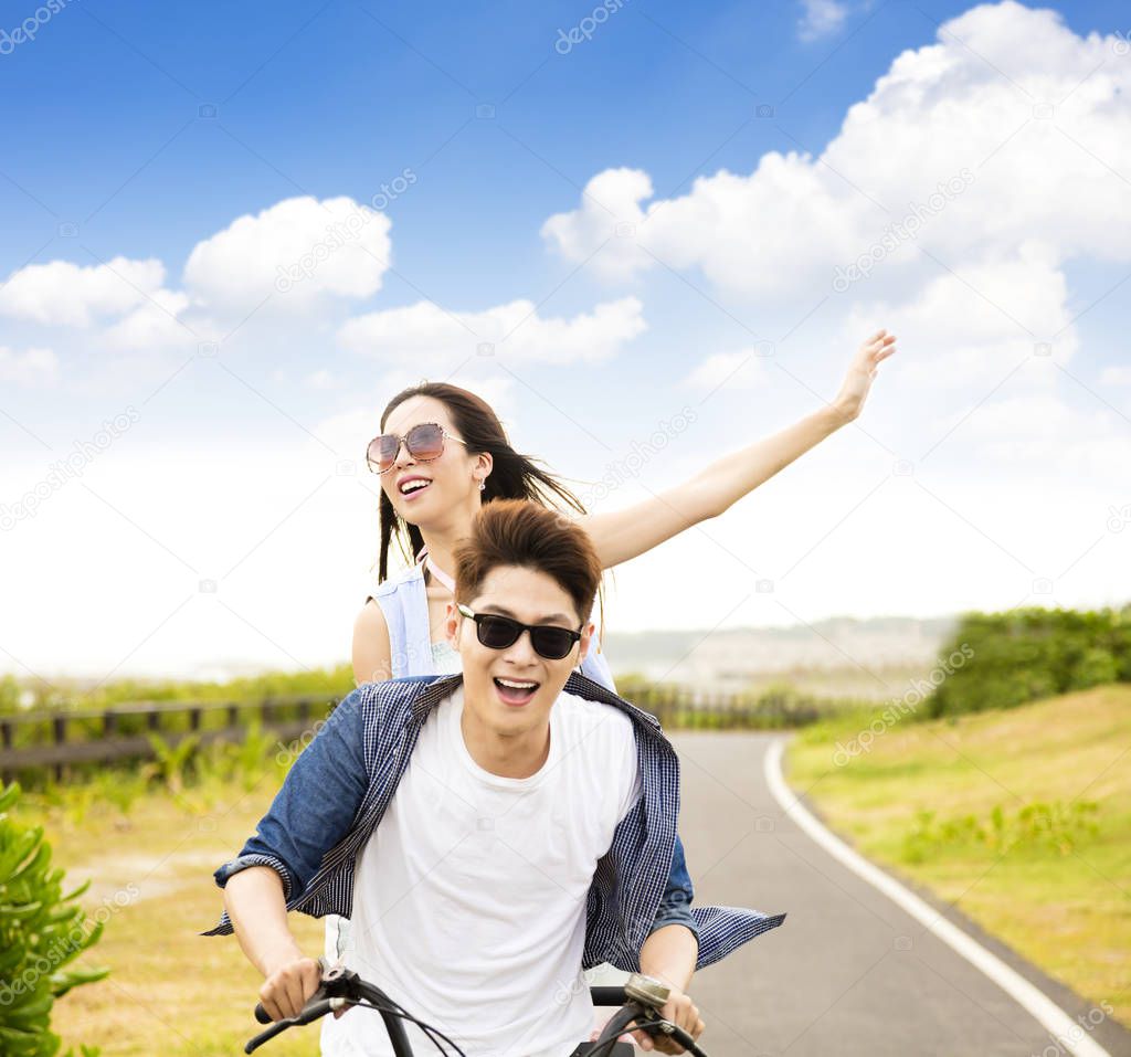 happy young couple riding bicycle  in the park