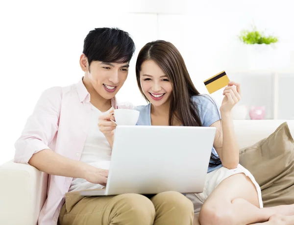 Feliz jovem casal sentado no sofá com laptop — Fotografia de Stock