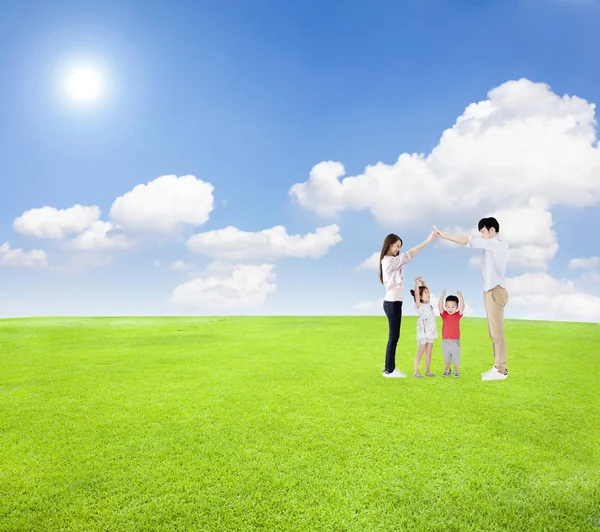 Familia feliz divirtiéndose junto con fondo de nube de campo verde Fotos De Stock