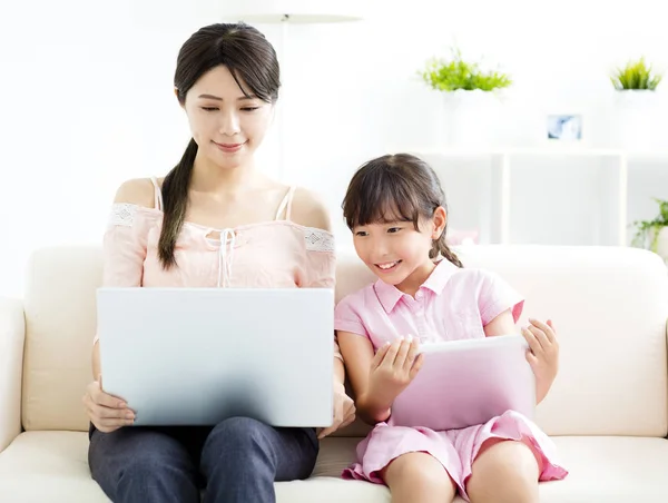 Mãe com filha olhando para Laptop no sofá — Fotografia de Stock