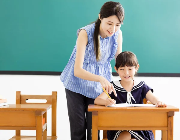 Młody nauczyciel pomaga dziecko z pisaniem lekcji — Zdjęcie stockowe
