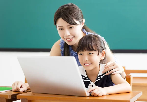 Joven maestro ayudando a niño con lección de computadora — Foto de Stock