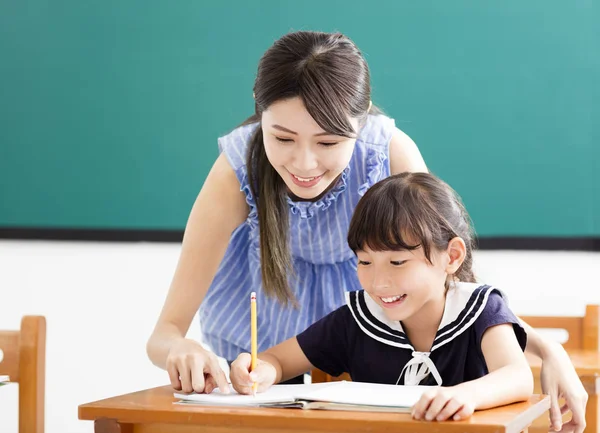 Junge Lehrerin hilft Kind bei Schreibstunde — Stockfoto