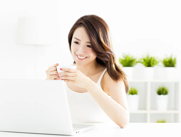 Sorrindo jovem mulher com laptop na sala de estar — Fotografia de Stock