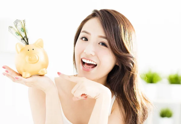 Feliz jovem mulher mostrando porquinho banco com dinheiro — Fotografia de Stock