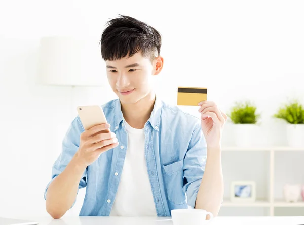 Молодой человек покупает онлайн с помощью кредитной карты и смартфона — стоковое фото