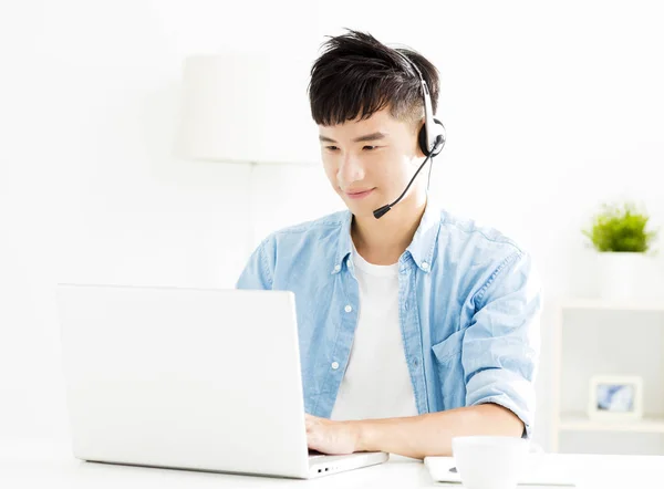 Jovem feliz com fone de ouvido e olhando para laptop — Fotografia de Stock