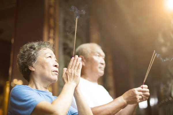 Couple de personnes âgées priant Bouddha avec bâton d'encens au temple — Photo