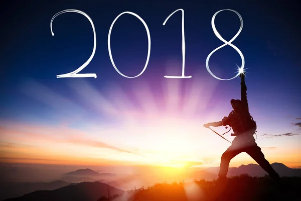 Conceito feliz ano novo. homem desenho 2018 por lanterna no topo da montanha — Fotografia de Stock