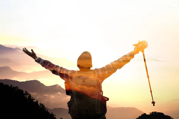 Человек с двойной экспозицией на вершине горы наблюдает за восходом солнца — стоковое фото