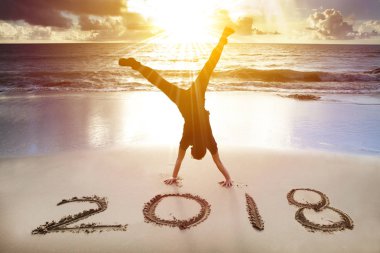  man handstand on the beach.happy new year 2018 concept clipart