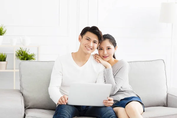 Mutlu genç çift kanepede dizüstü bilgisayar ile — Stok fotoğraf