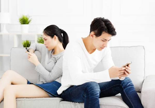 Pár na gauči a sleduje jejich telefony — Stock fotografie