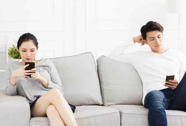 Couple sur le canapé et regarder leurs téléphones — Photo