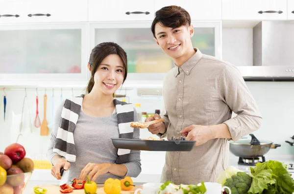 Gelukkige jonge paar koken in de keuken Rechtenvrije Stockfoto's