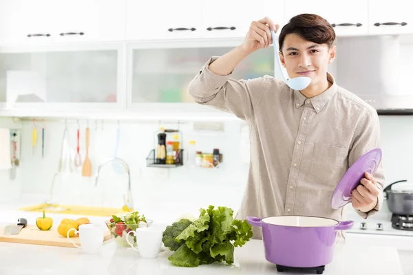 Młody człowiek, gotowanie w domu w kuchni — Zdjęcie stockowe