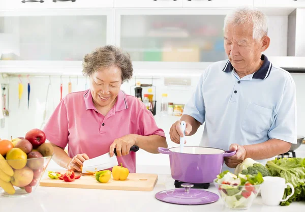 Happy senior couple cooking in kitchen — Stock Photo, Image