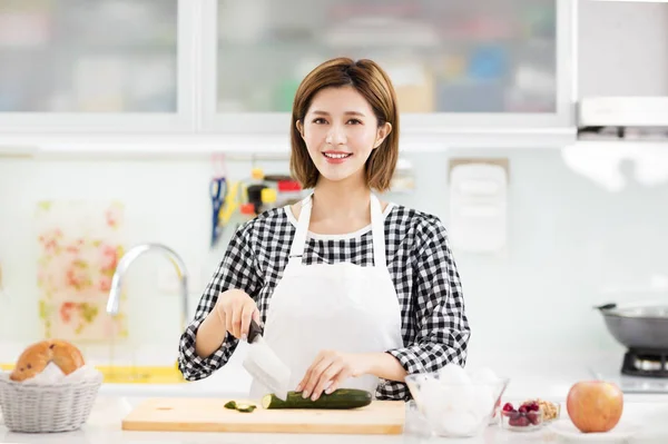 台所で料理を若い女性の笑みを浮かべてください — ストック写真