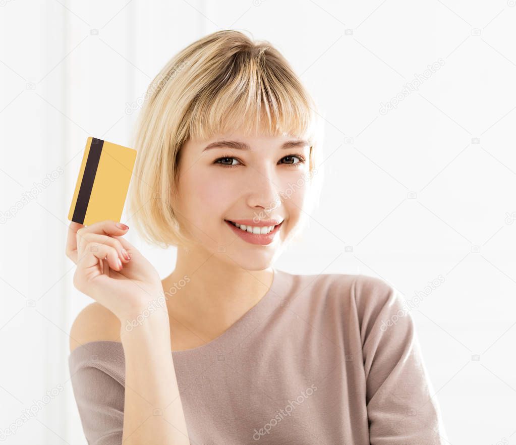 Smiling young woman showing credit car