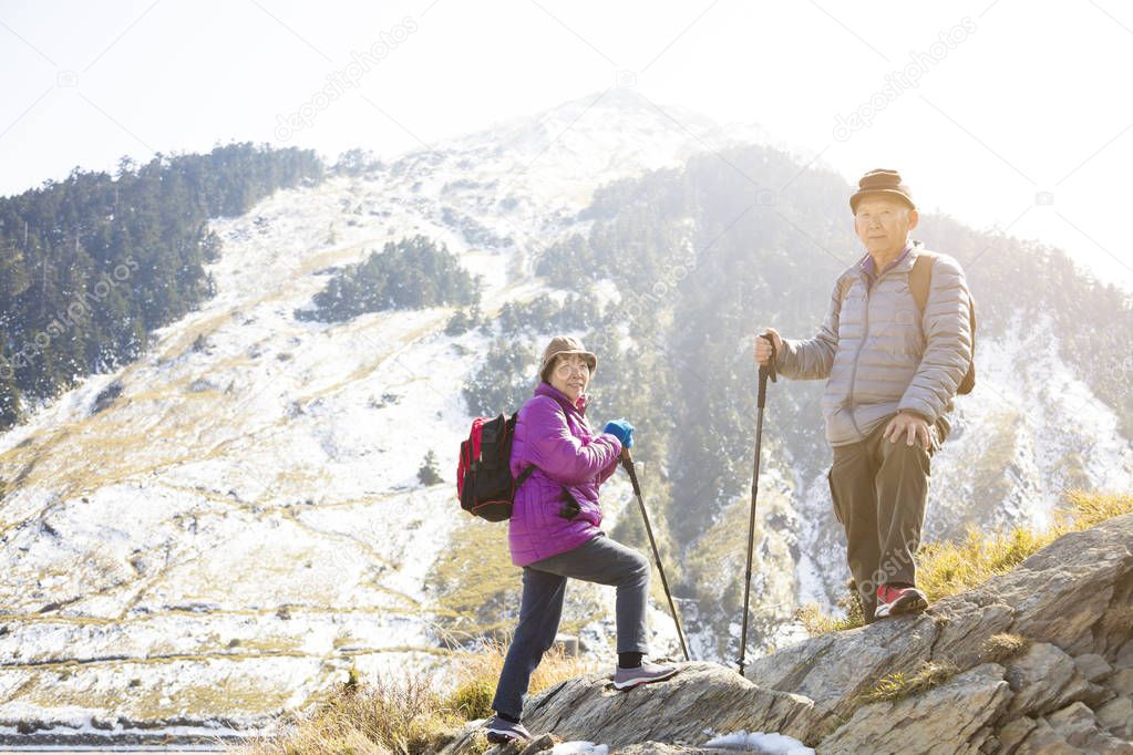 happy senior couple hiking on the mountain