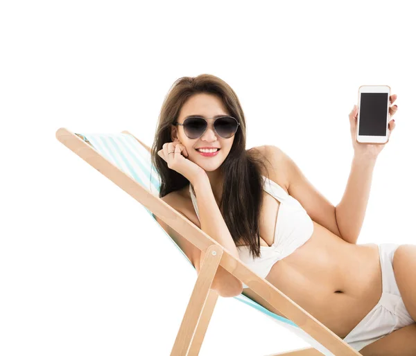 Young woman in lounge chair and showing smart phone — Stock Photo, Image