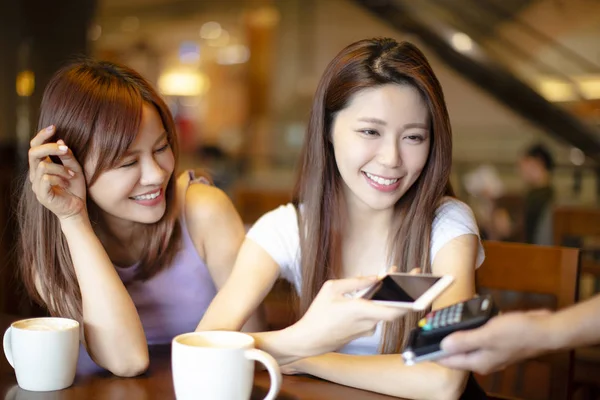 Женщина платит мобильным телефоном в кафе-магазине — стоковое фото