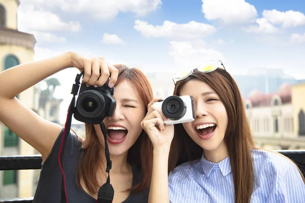 Дві щасливі дівчата тримають камеру і концепцію подорожей — стокове фото