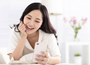 kanepede oturan ve akıllı telefon izlerken mutlu kadın