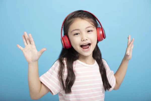 Heureuse petite fille avec écouteurs écouter et chanter chanson — Photo