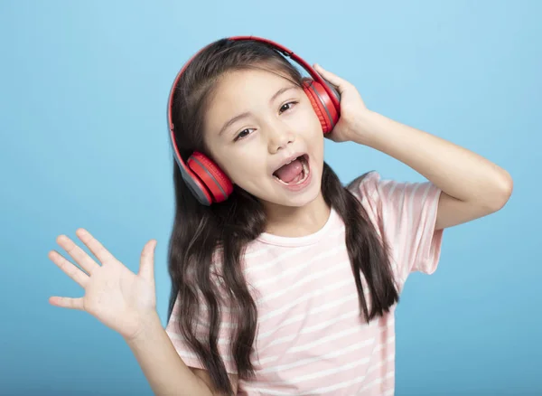 Glückliches kleines Mädchen mit Kopfhörern hört zu und singt ein Lied — Stockfoto