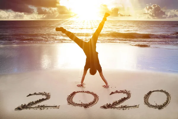 Hombre handstand en el concepto beach.happy año nuevo 2020 —  Fotos de Stock