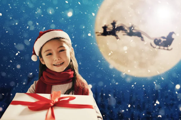 Cute little girl with christmas presents. Santa Claus flying in — Stock Photo, Image