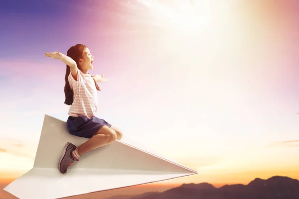 Menina feliz no avião de papel e voando no céu — Fotografia de Stock