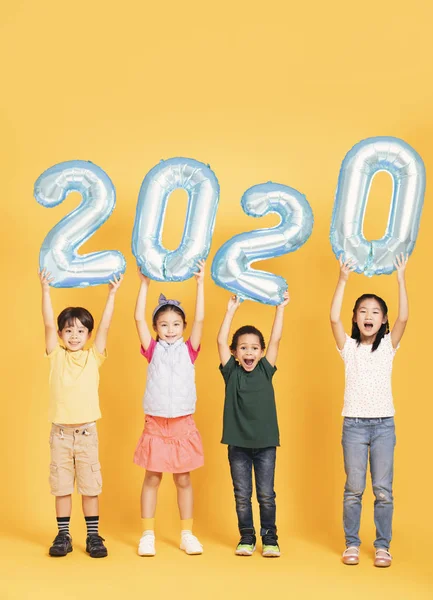 Groupe d'enfants heureux célébrant et montrant 2020 nouvelle année concéder — Photo