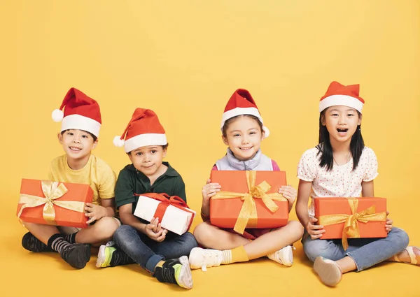 Groep van gelukkige jonge geitjes in kerstmuts met presenteert — Stockfoto