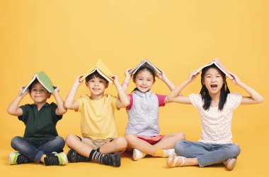 Mutlu çocuklar yerde birlikte oturuyorlar.