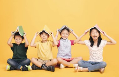 Mutlu çocuklar yerde birlikte oturuyorlar.