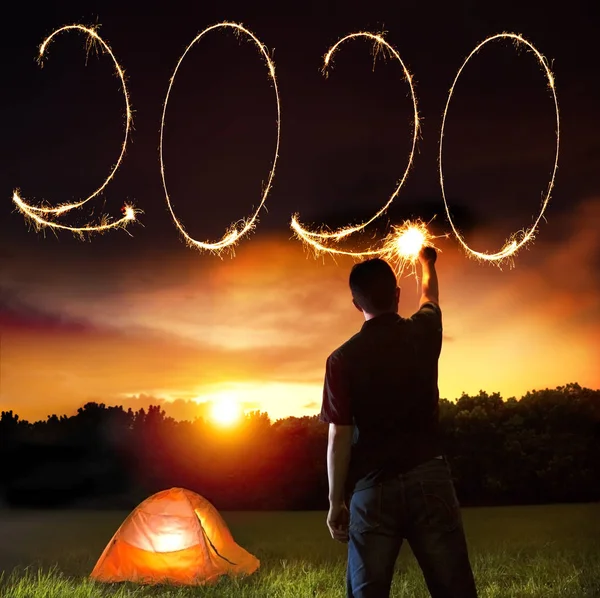 Jovem celebrando e desenhando 2020 ano novo por brilhos — Fotografia de Stock