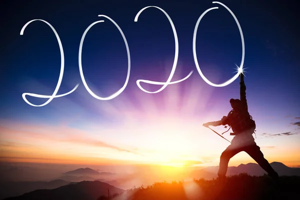 Man celebrating and drawing 2020 new year on the mountain — ストック写真