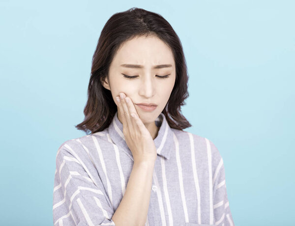 young woman touching mouth with hand with painful expression