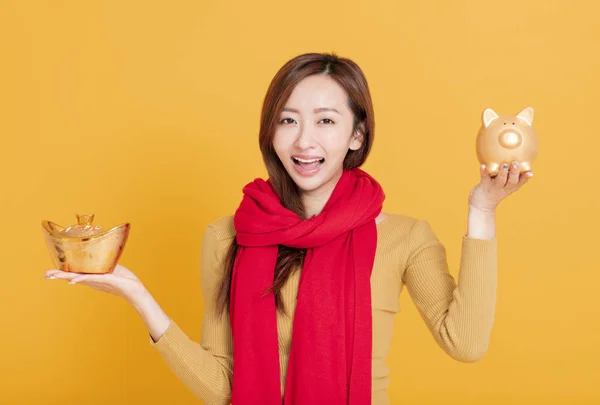 Bela ásia jovem mulher mostrando chinês ouro lingote e porquinho — Fotografia de Stock