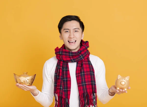 Gelukkig aziatische jongeman tonen chinese goud ingot en piggy bank — Stockfoto