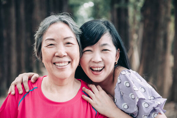 asian senior mother and her adult daughter are hugging