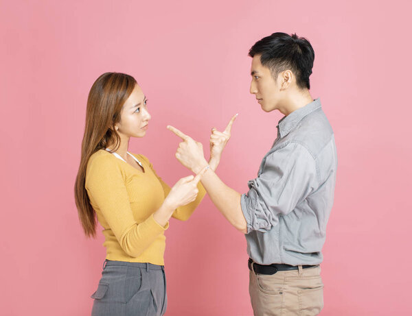 Angry couple pointing at each other while arguing