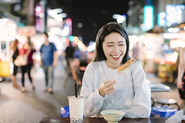 アジアの若い女性はナイトマーケットでストリートフードを楽しむ — ストック写真