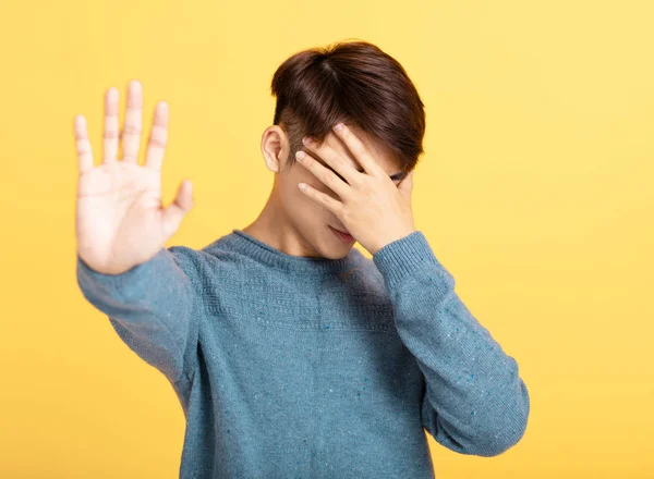 Młody człowiek pokazuje swoją dłoń ukrywając twarz — Zdjęcie stockowe